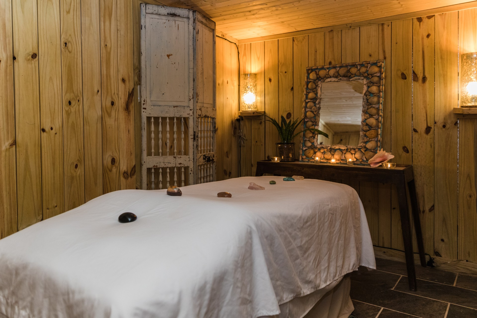 Candlelit massage room with white linens and healing crystals