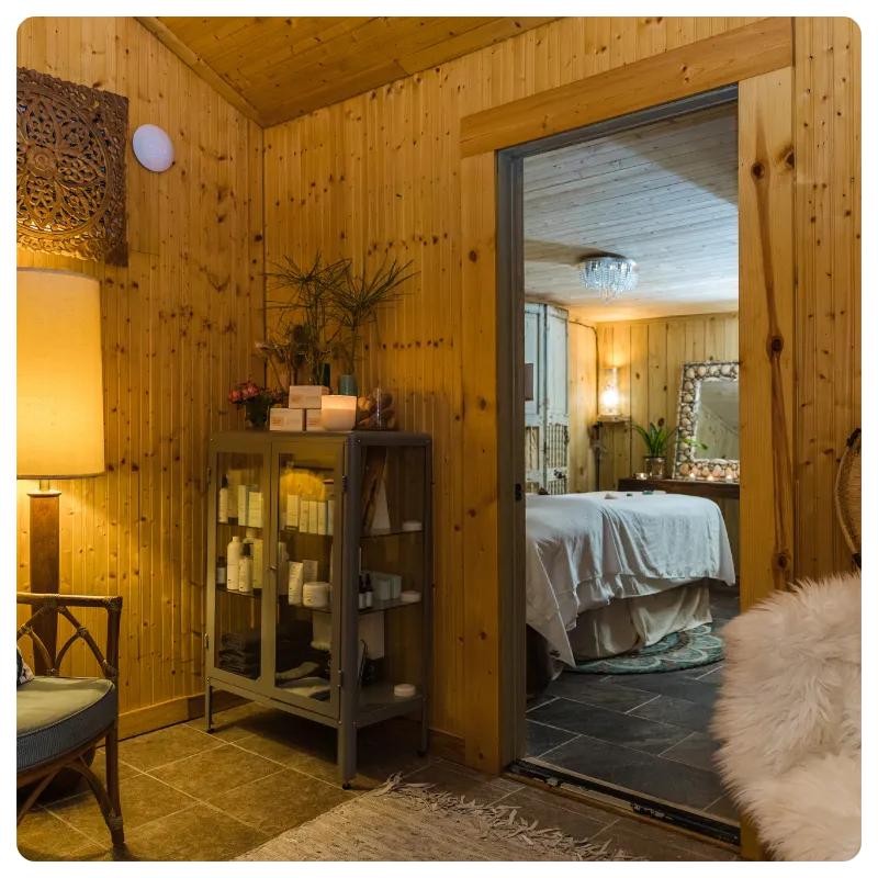 Warm cedar treatment room with soft lamplight and a linen-draped massage table