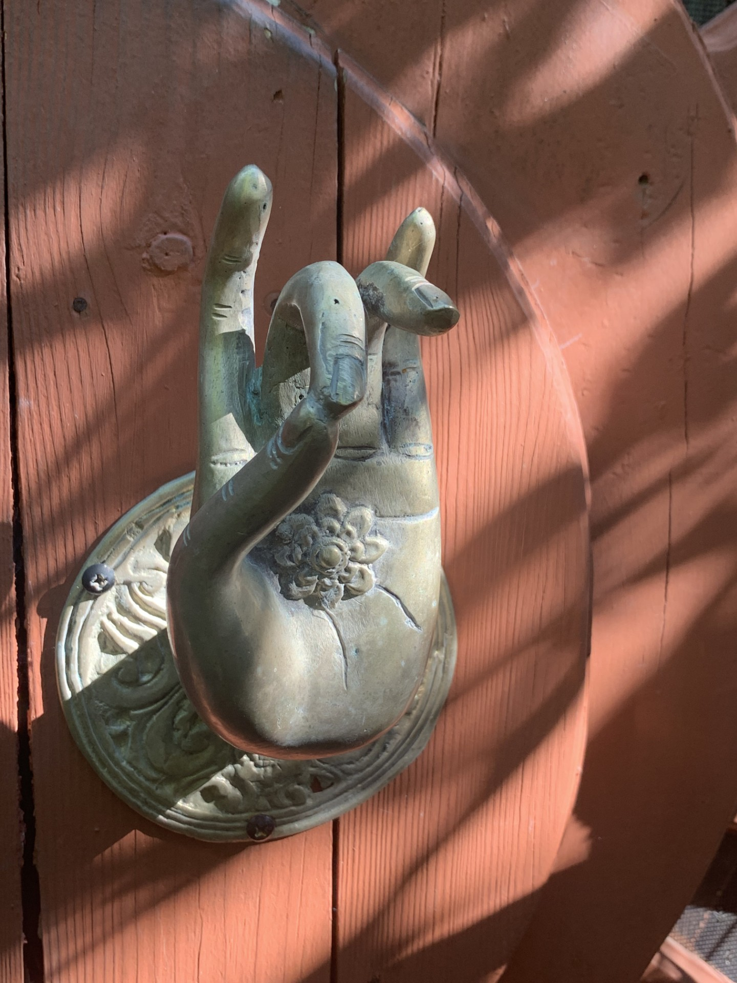 Brass hand door knocker on the bungalow's orange door
