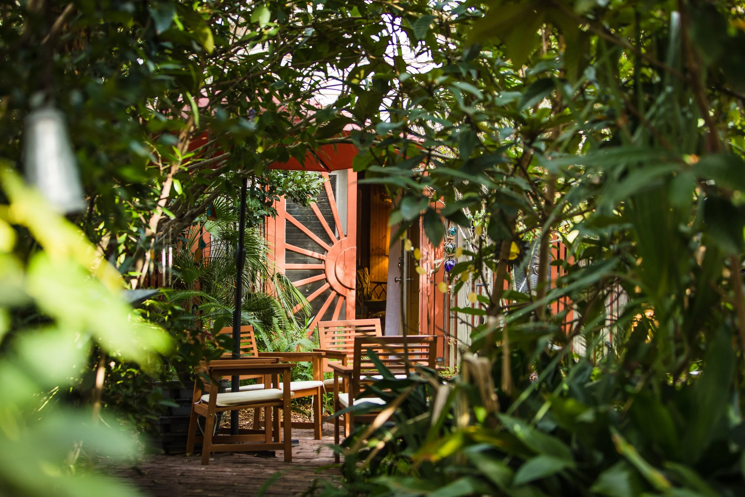 The bright orange front door of the Folly Beach Medi Spa bungalow surrounded by tropical greenery